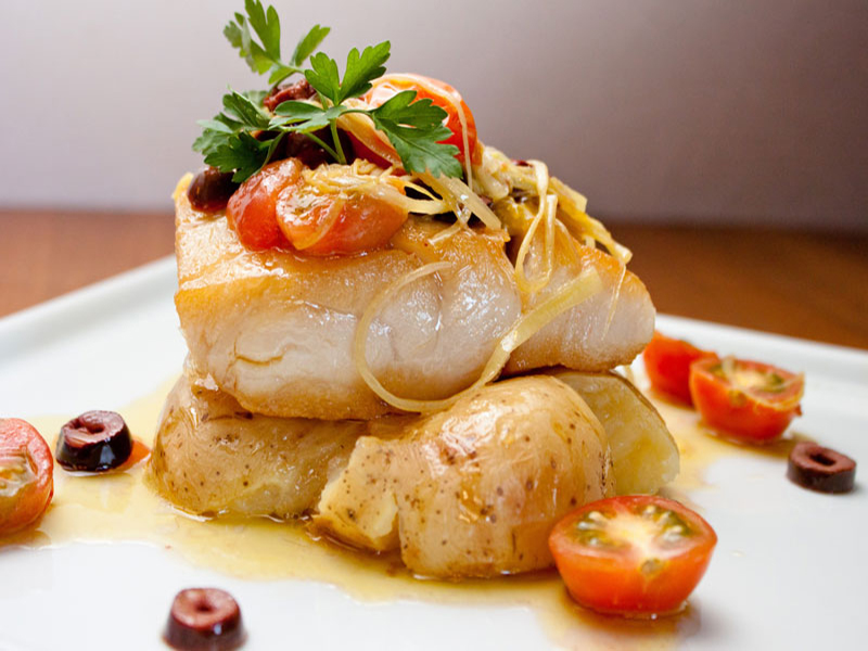 a slice of cod with potatoes and tomato