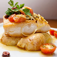 a slice of cod with potatoes and tomato