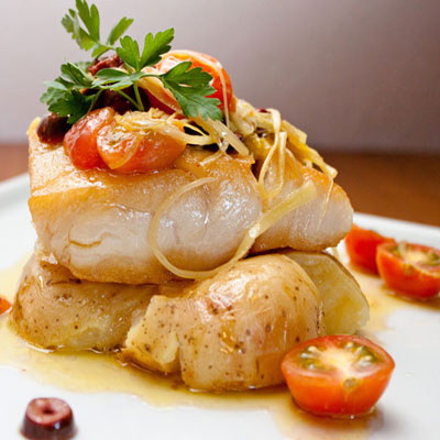 a slice of cod with potatoes and tomatoes